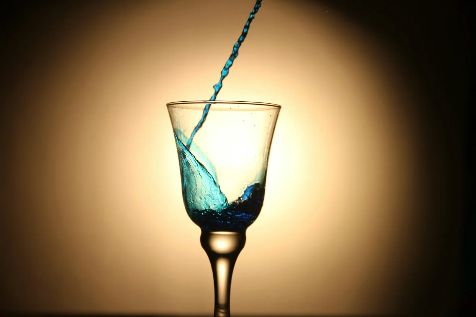 Blue liquid pouring into a wine glass, representing DynastyProcess blending ADP data with expert consensus rankings